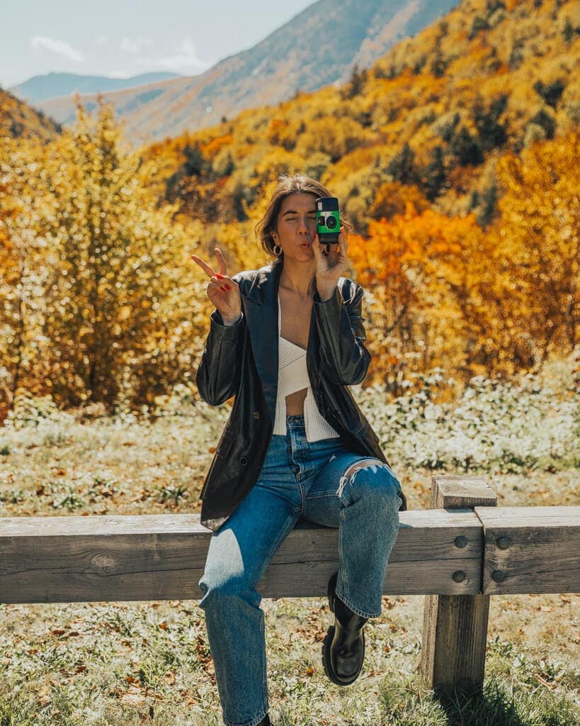 girl taking a picture in crawford notch state park new hampshire in the fall