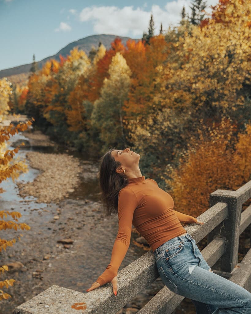 girl admiring fall colors on a new england fall road trip itinerary through the white mountains nh