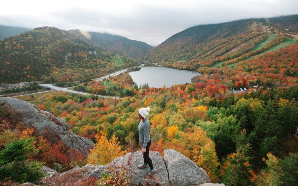 girl looking at yellow and orange fall foliage in new england's franconia notch state park
